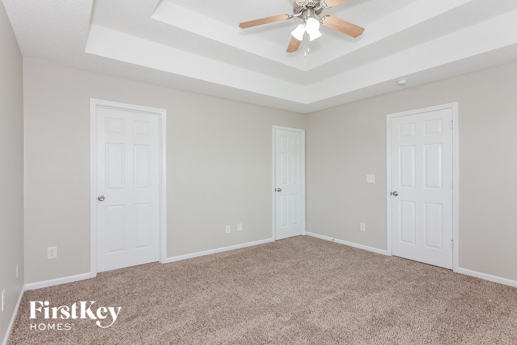 a bedroom with two doors and a ceiling fan