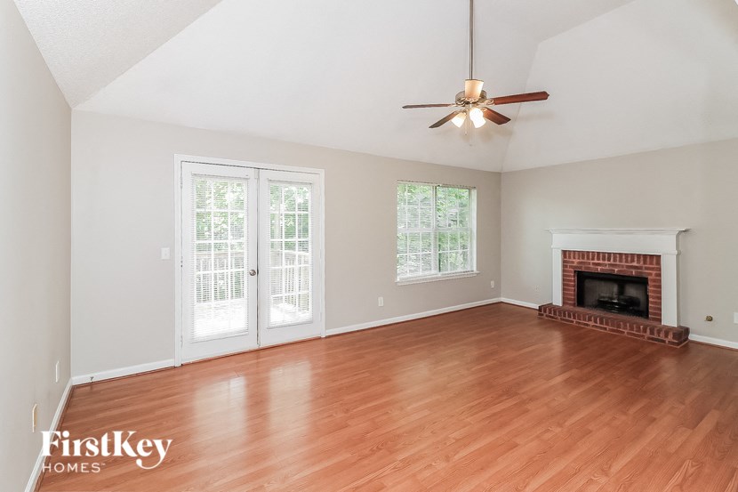 an empty living room with a fireplace and a ceiling fan