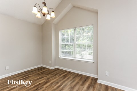 A room with wooden floors and a window with blinds.