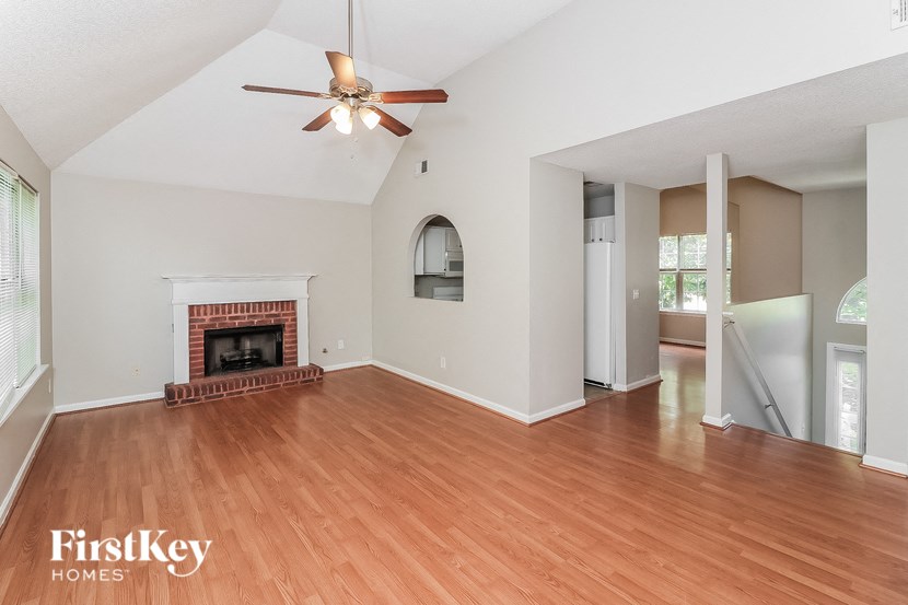 an empty living room with a fireplace and a ceiling fan