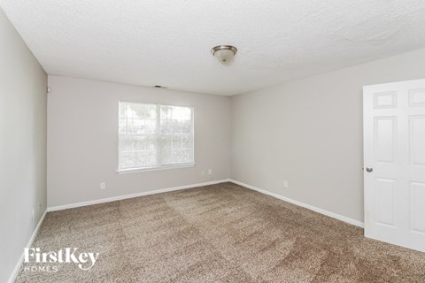 a spacious living room with carpet and a white door
