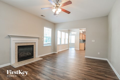 A spacious room with a fireplace and wooden flooring.