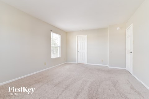 a spacious living room with carpet and a white door