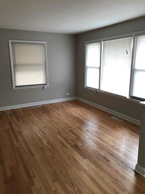 a living room with a hard wood floor and two windows