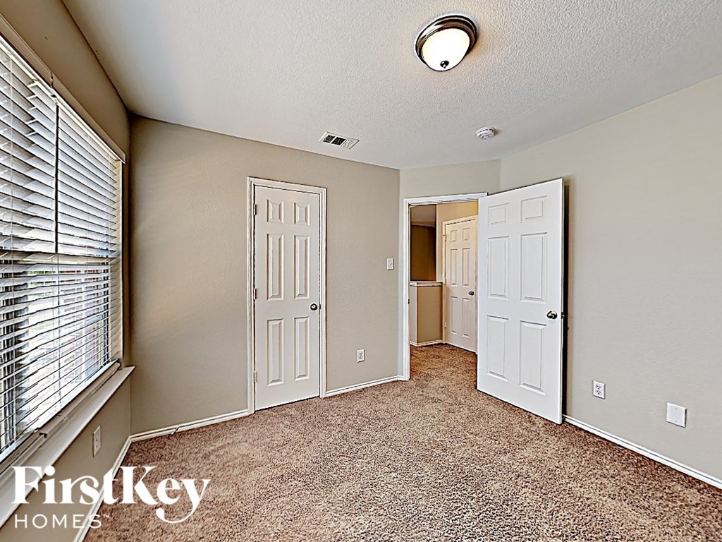 an empty bedroom with two doors and a window