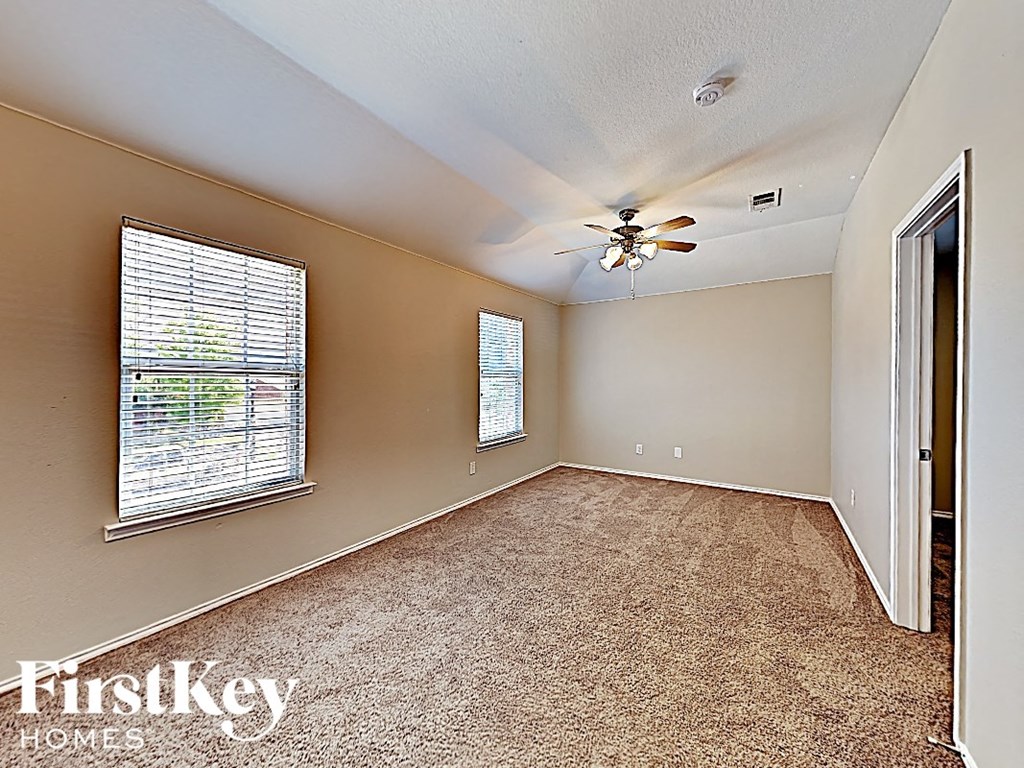 an empty bedroom with a ceiling fan and a window
