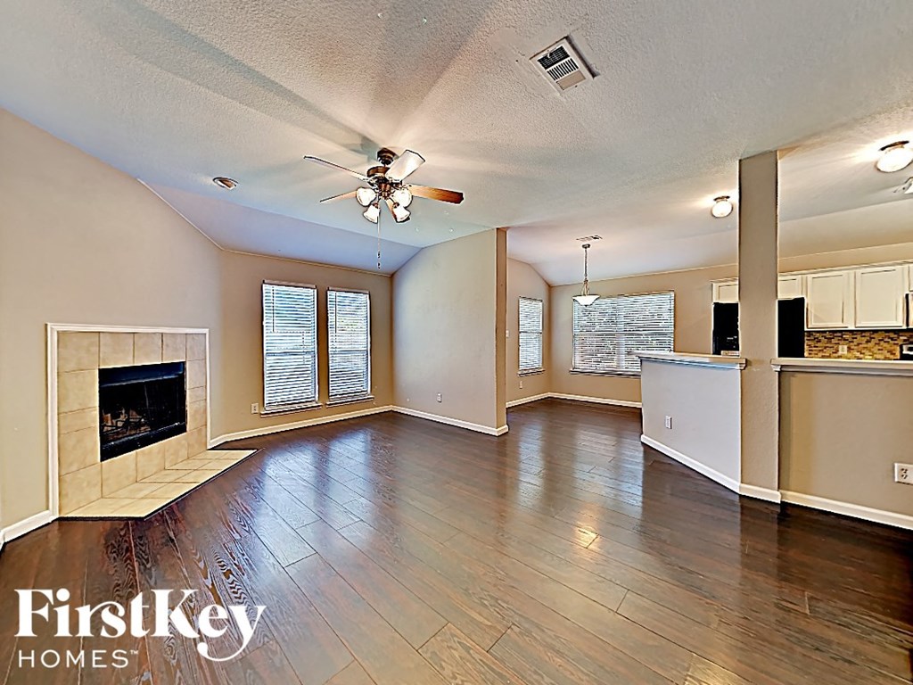 an empty living room with a fireplace and a ceiling fan