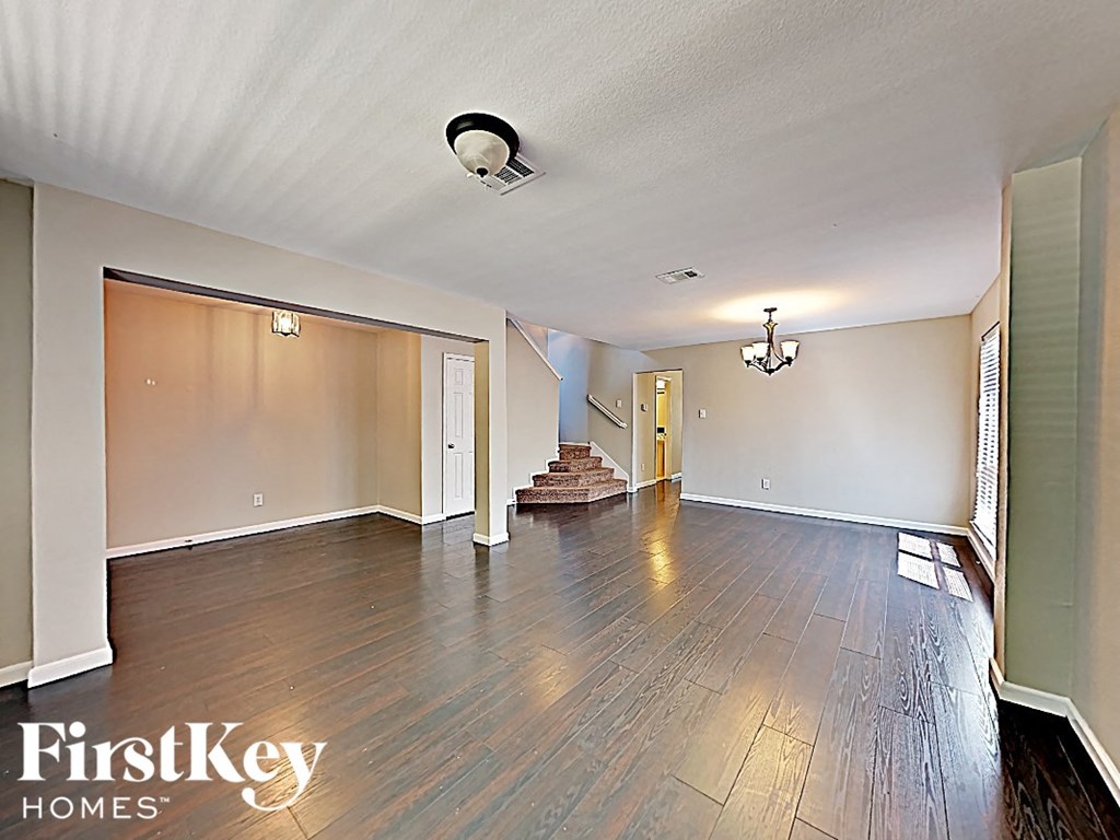 an empty living room with wood floors and a staircase