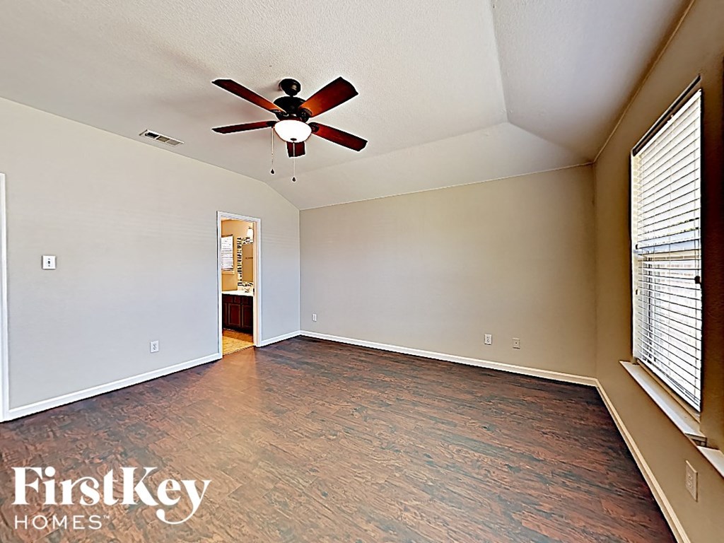 an empty living room with a ceiling fan and a large window