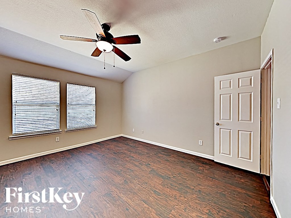 an empty living room with a ceiling fan and window
