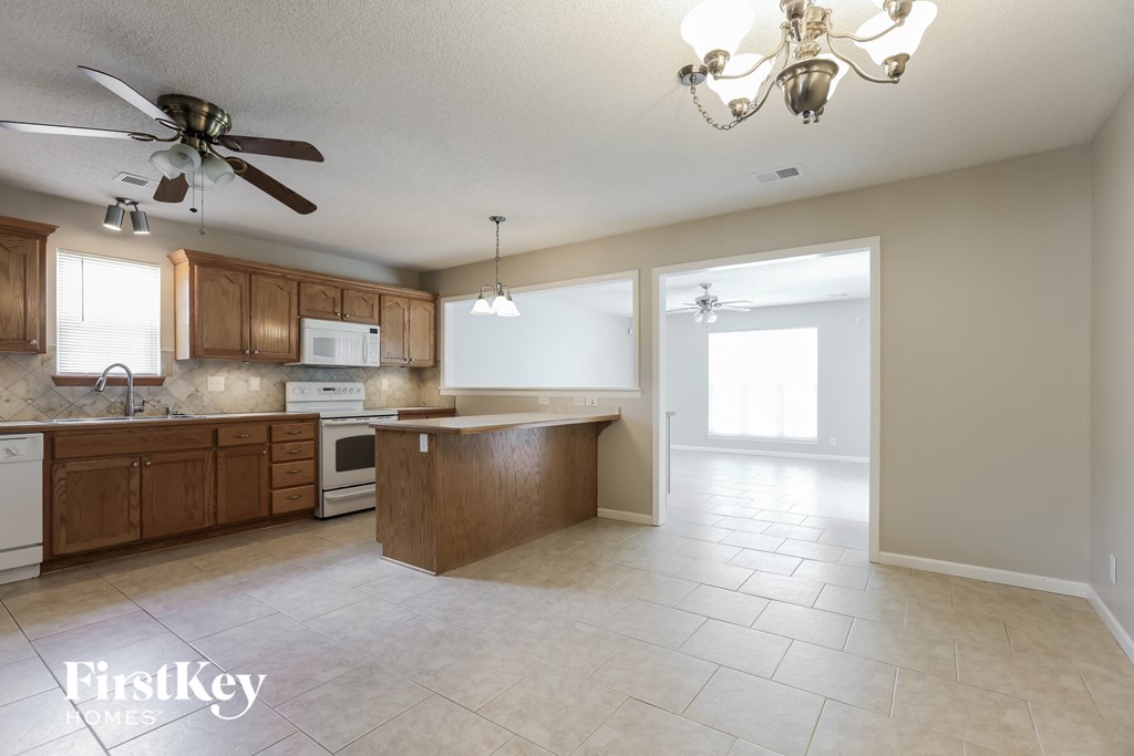 a kitchen with wooden cabinets and tiled floors and a ceiling fan