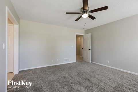 a spacious living room with carpet and a ceiling fan