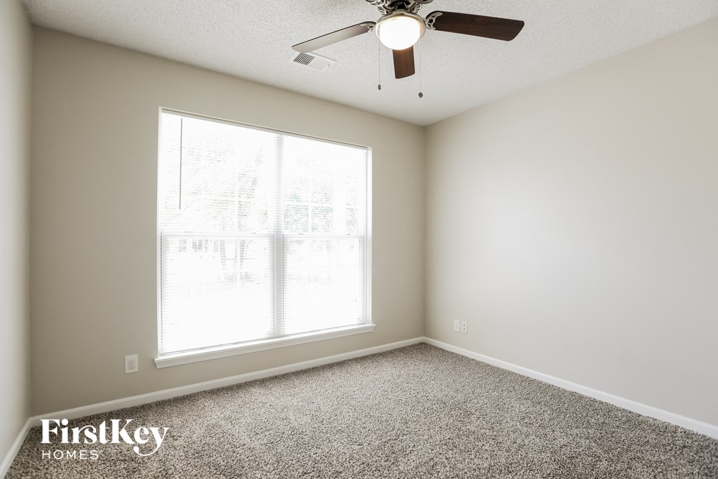 a bedroom with a large window and a ceiling fan