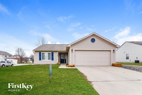 a white and blue house with a driveway and lawn