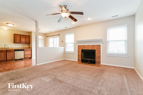 an empty living room with a fireplace and a ceiling fan