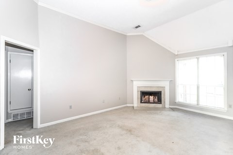 A spacious living room with a fireplace and a door on the left.