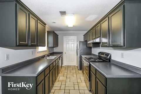 A kitchen with dark green cabinets and a white door in the middle.