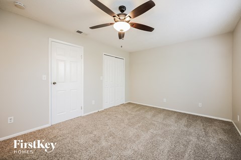 the spacious living room with ceiling fan and carpet