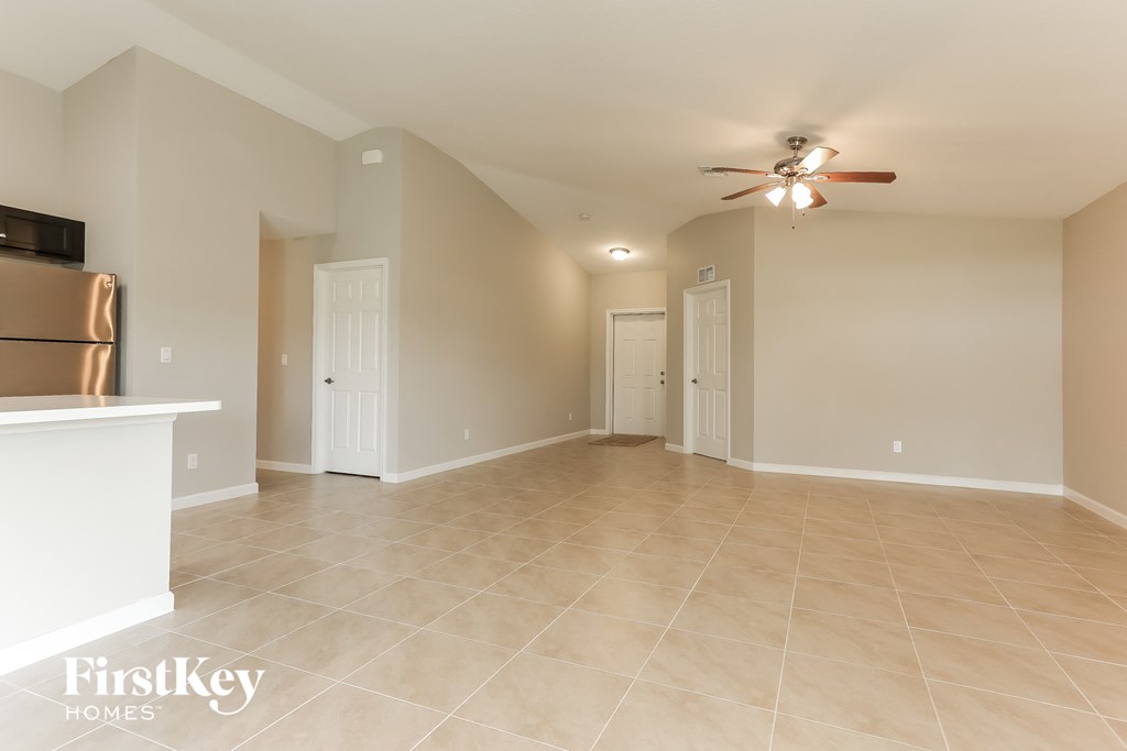 a spacious living room with tile flooring and a ceiling fan