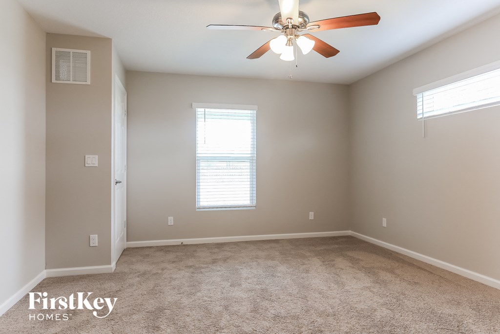 a carpeted room with a ceiling fan and a window