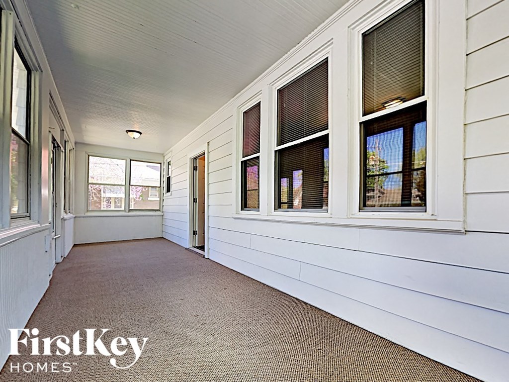 a covered porch with white siding and windows