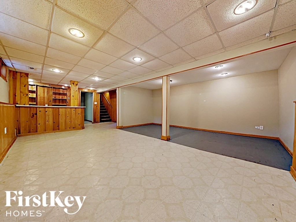an empty basement with a tile floor and white walls
