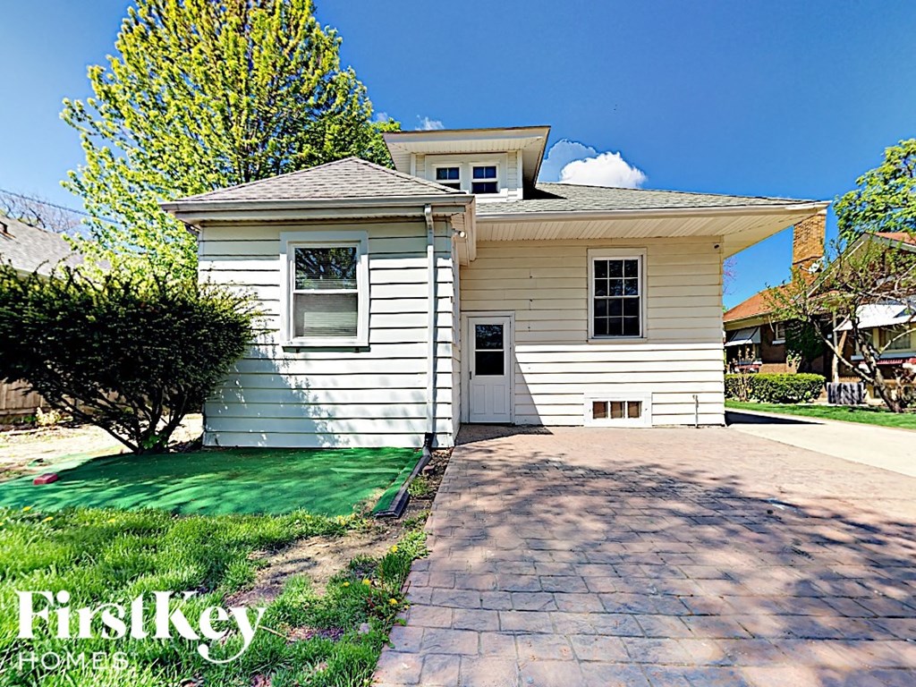 a small white house with a driveway and grass