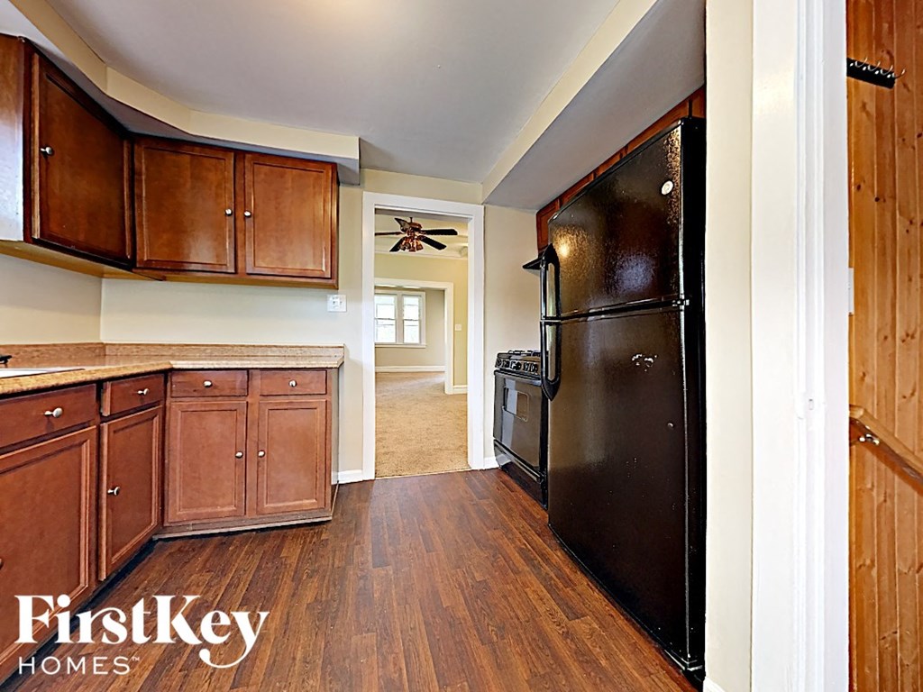 a kitchen with a black refrigerator and wooden cabinets