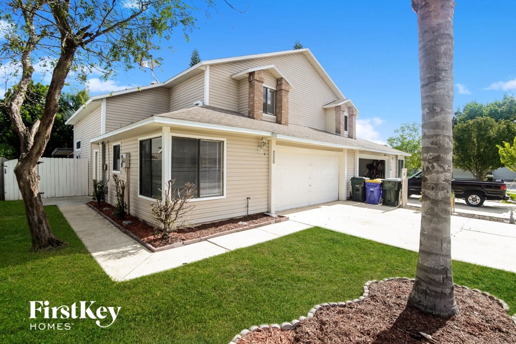 a white and tan house with a yard and a tree