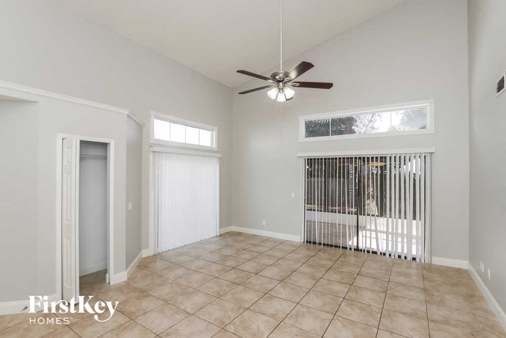 an empty living room with a ceiling fan and a window