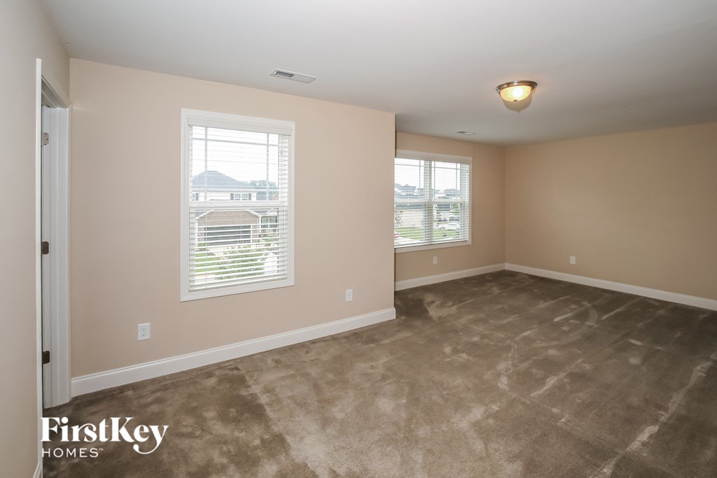 the living room of a home with a carpeted floor and two windows