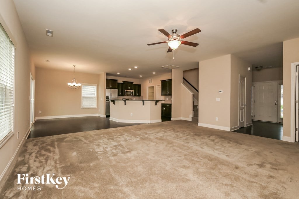 an empty living room and kitchen with a ceiling fan