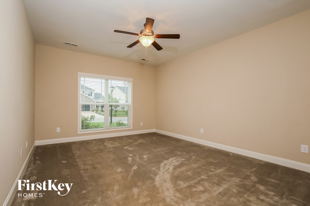 a empty living room with a ceiling fan and a window