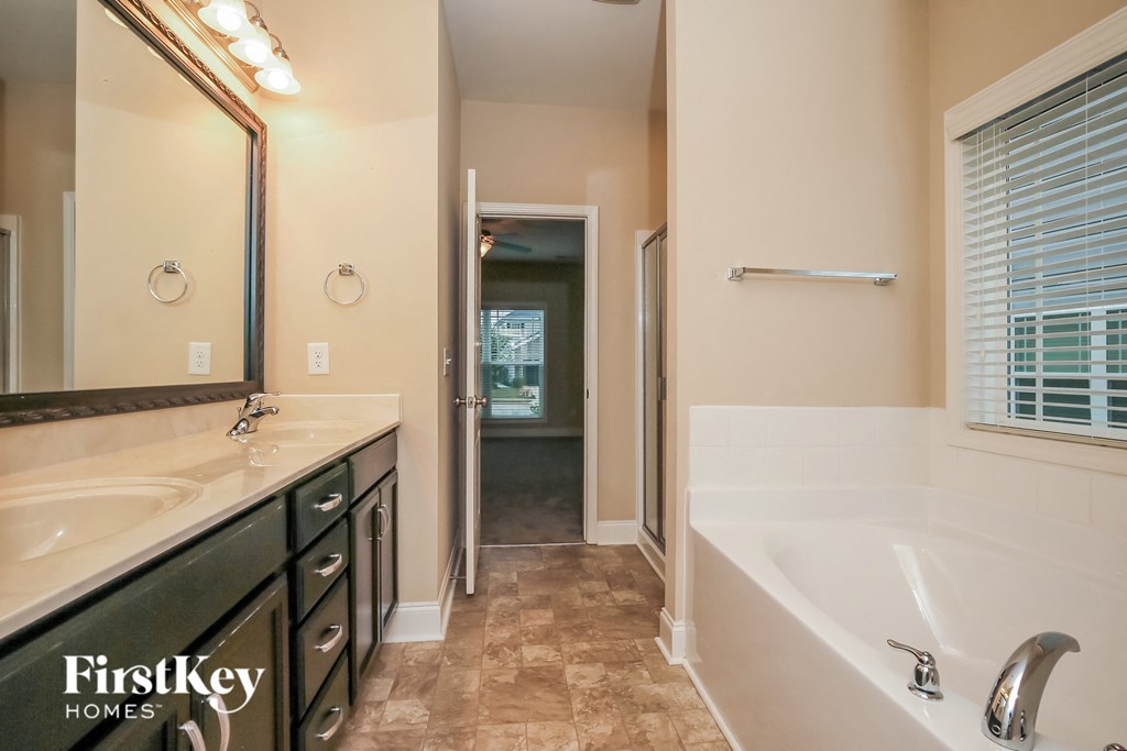 the master ensuite bathroom has a large tub and a large vanity with a mirror