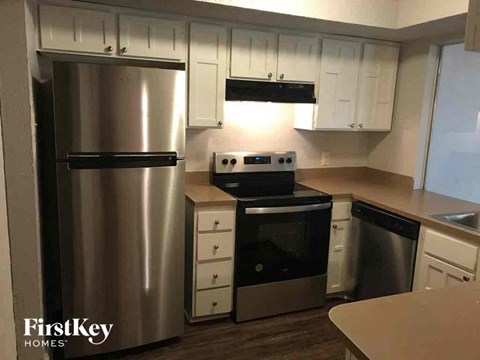 A kitchen with a stainless steel refrigerator and a stove top oven.