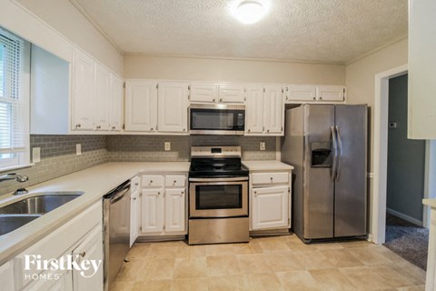 a kitchen with white cabinets and stainless steel appliances