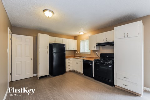 A kitchen with white cabinets and black appliances.