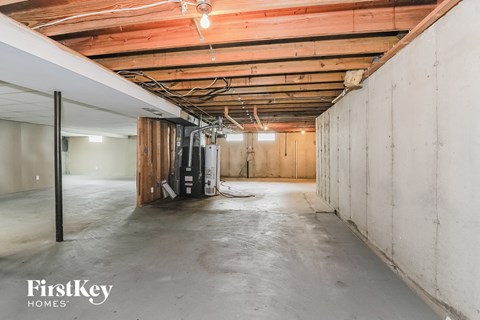 A spacious unfinished room with wooden beams on the ceiling and a concrete floor.