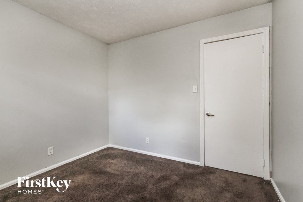 A room with a carpeted floor and a white door.