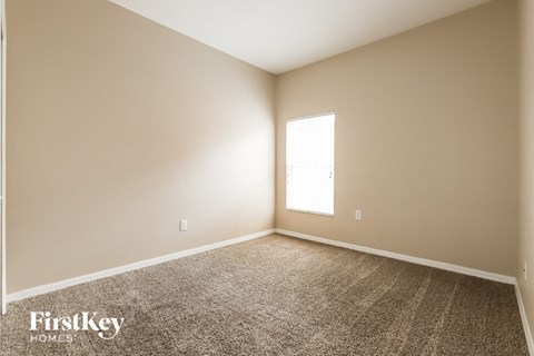 the living room of a new home with carpet and a window
