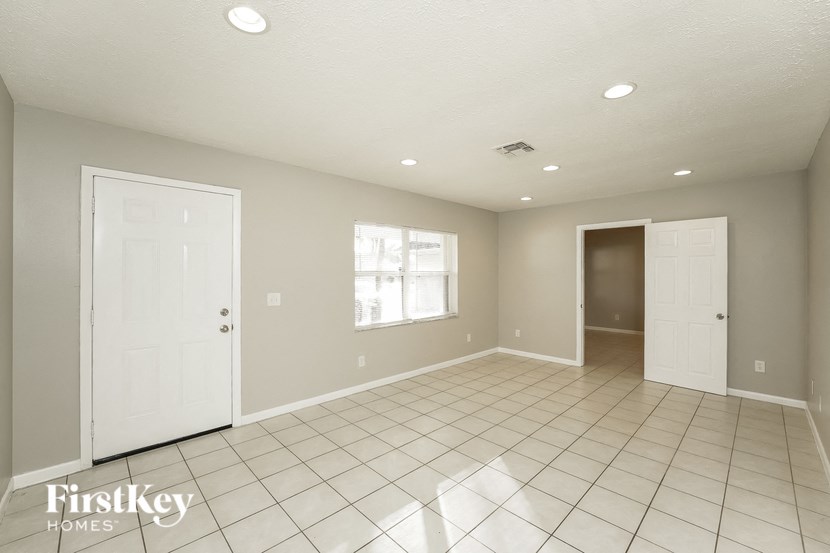 a living room with a white tile floor and a white door