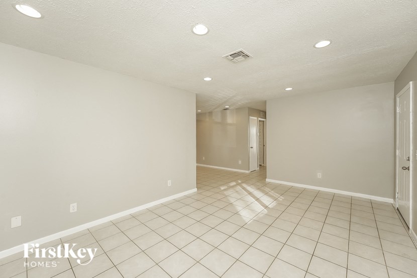 a spacious living room with tile flooring and a door to a hallway