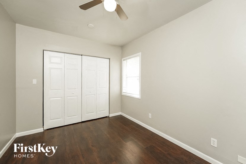 a bedroom with white walls and wood floors and a ceiling fan