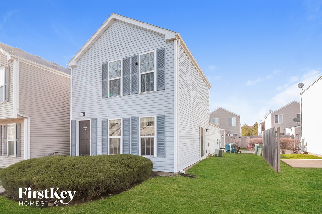 a white house with blue shutters and a green lawn