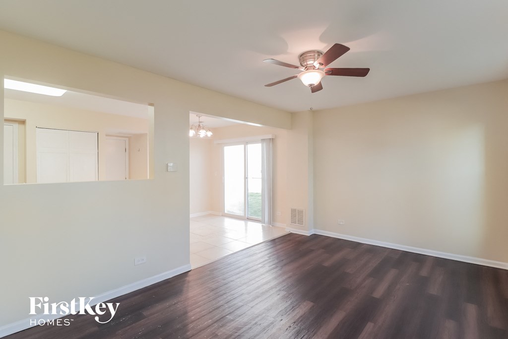 an empty living room with wood floors and a ceiling fan