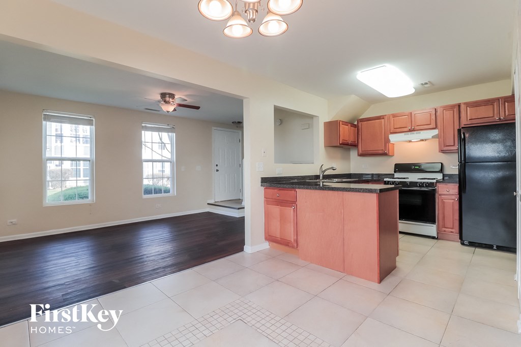 a kitchen with wood cabinets and black appliances and a white tile floor