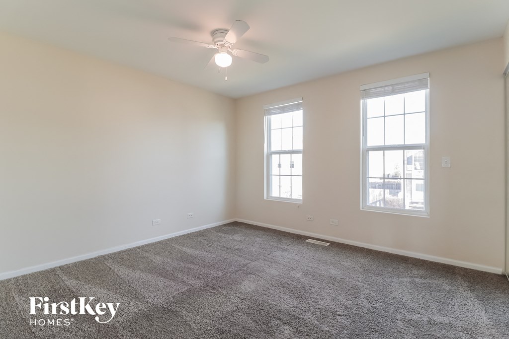the living room of an empty house with a ceiling fan and two windows