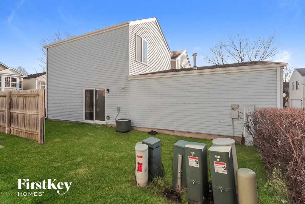 a backyard with green grass and a white house and a yard with green trash cans