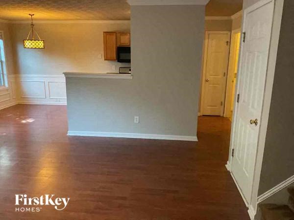 an empty living room with a kitchen and a door way