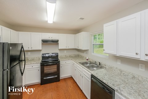 a kitchen with white cabinets and granite counter tops and black appliances